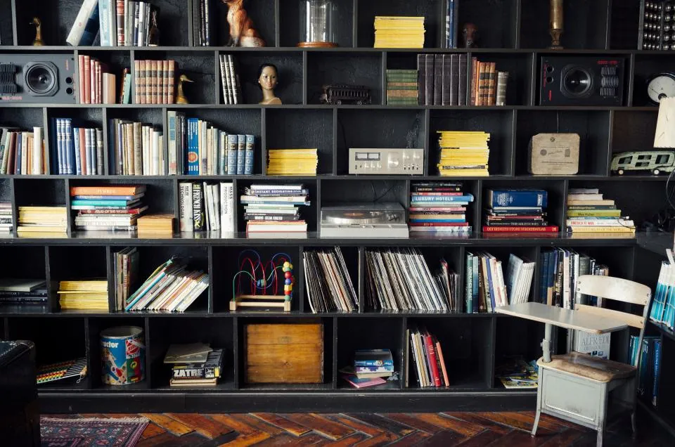 Dark wall shelves filled with books, records and objects