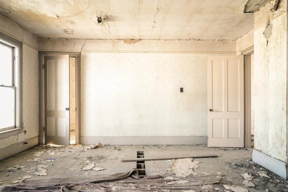 A room mid-demolition with stripped walls and debris on the floor