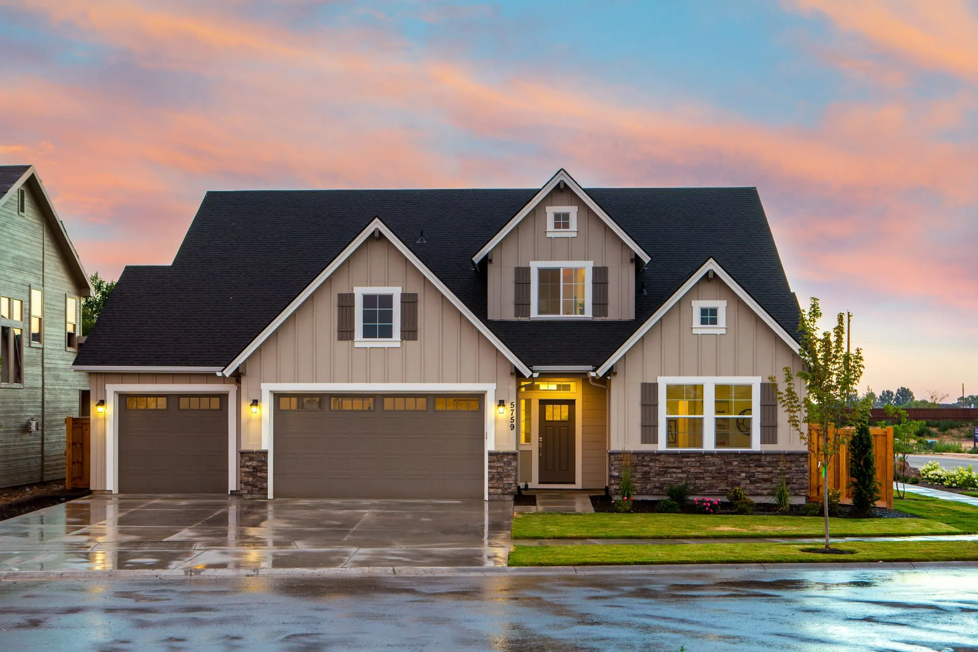 A two-story suburban house at dusk with a lit front porch