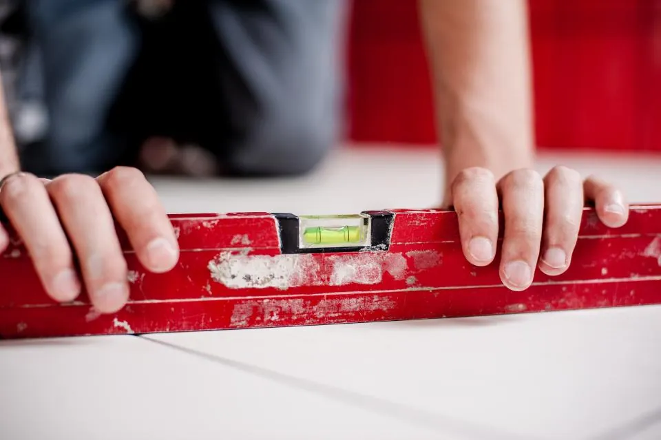 Hands with a red level checking a surface