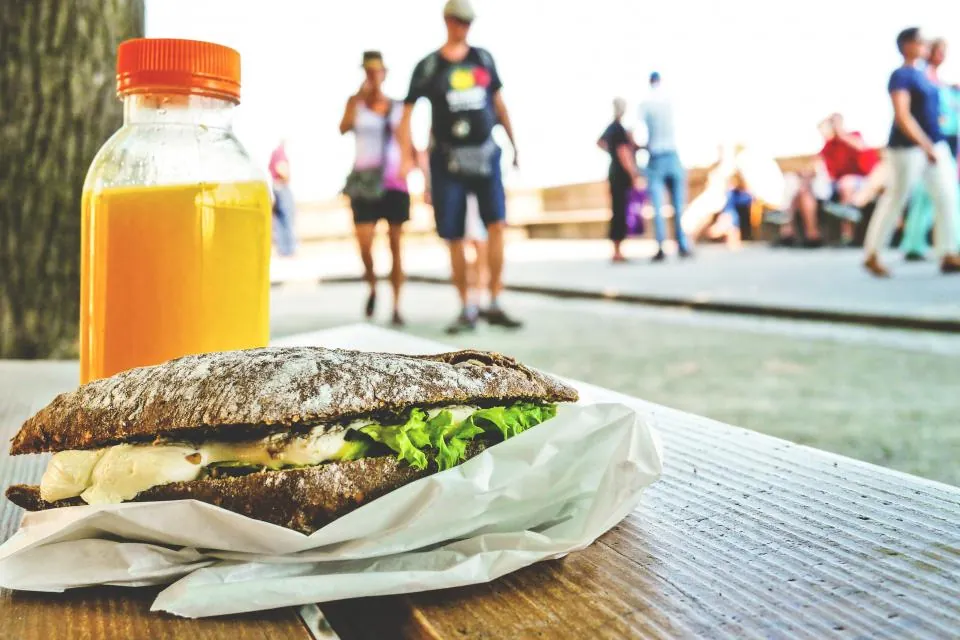 A stuffed sandwich and juice on an outdoor table