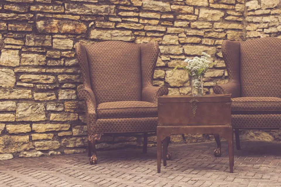 Two vintage wingback chairs against a stone wall